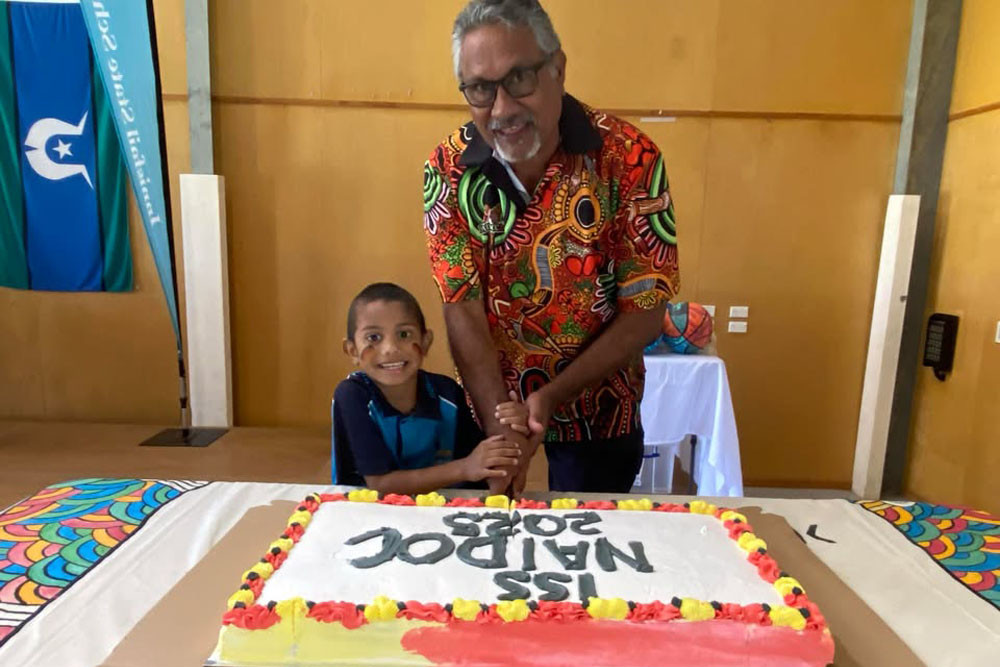Senior Police Liaison Officer Michael Sands and an Innisfail State School Prep student cut the special NAIDOC cake. Picture: Supplied